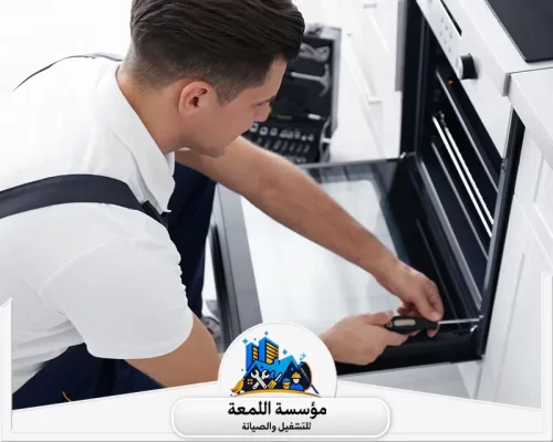 تصليح أفران الغاز بحفر الباطن _ 0565283428_ اللمعة خبير صيانة يستخدم مفكاً يدوياً لإصلاح وتثبيت مفصلات باب الفرن الزجاجي بعناية.