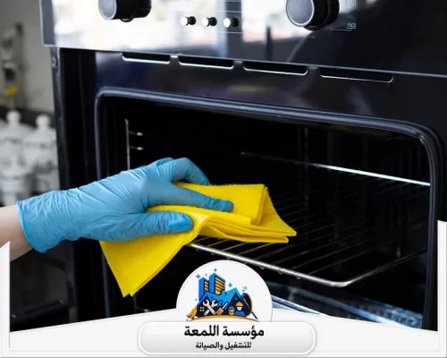 شركة تنظيف افران الغاز الرياض 0565283428 اللمعة أحد كوادر مؤسسة اللمعة المختصين وهو يقوم بعملية مسح دقيقة للأرفف الجانبية والهيكل الداخلي للفرن.